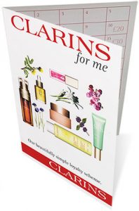 Clarins Double Serum surrounded by natural botanical ingredients and fresh flowers.