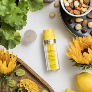 Clarins Double Serum surrounded by natural botanical ingredients and fresh flowers.